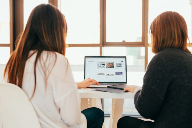 Zwei Frauen an einem Laptop, die in Wordpress arbeiten.