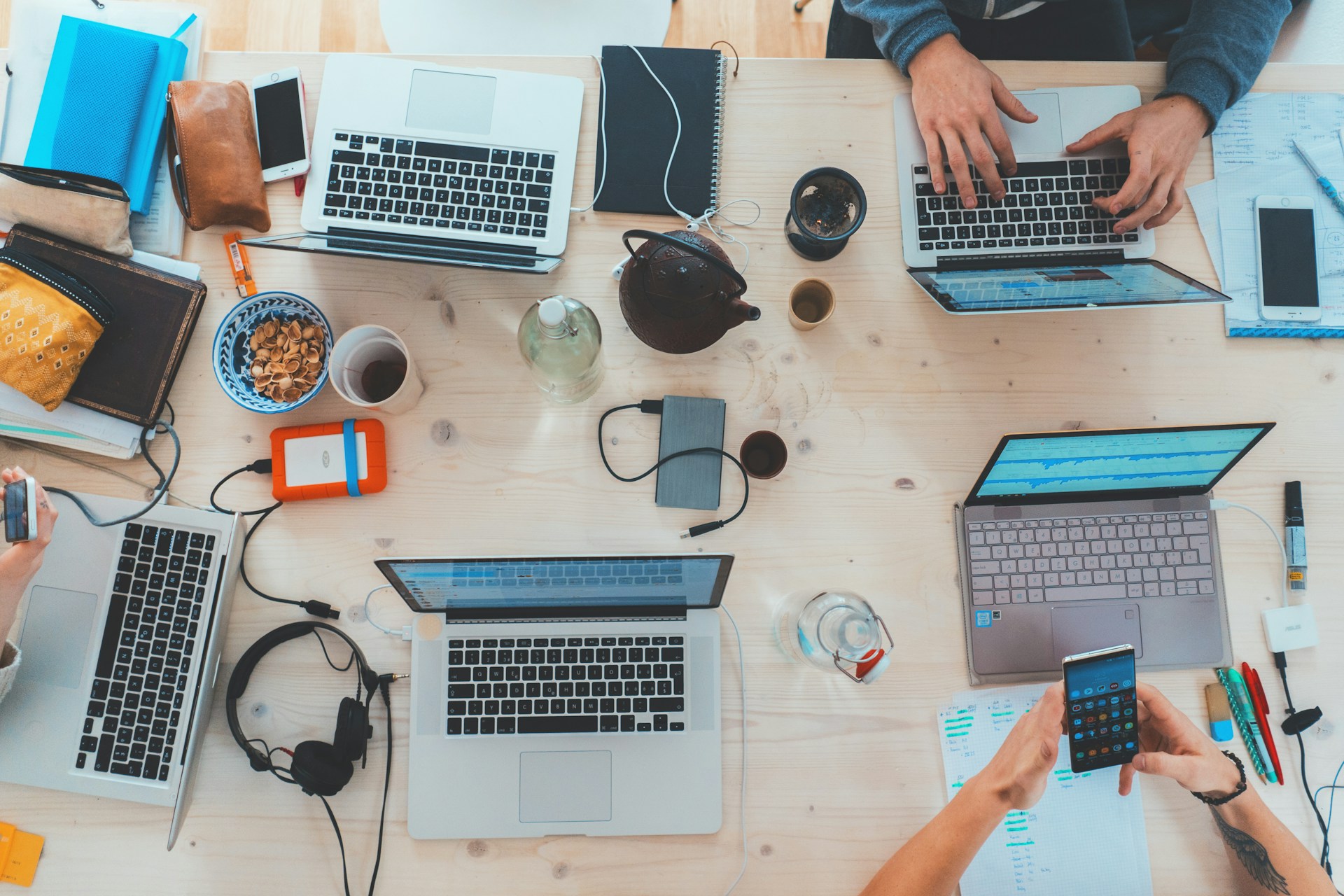 Eine Draufsicht auf einen Tisch mit Laptops - das Bild symbolisiert durch die Zusammenarbeit das neue samarbeid-Feature "automatisch teilnehmende"